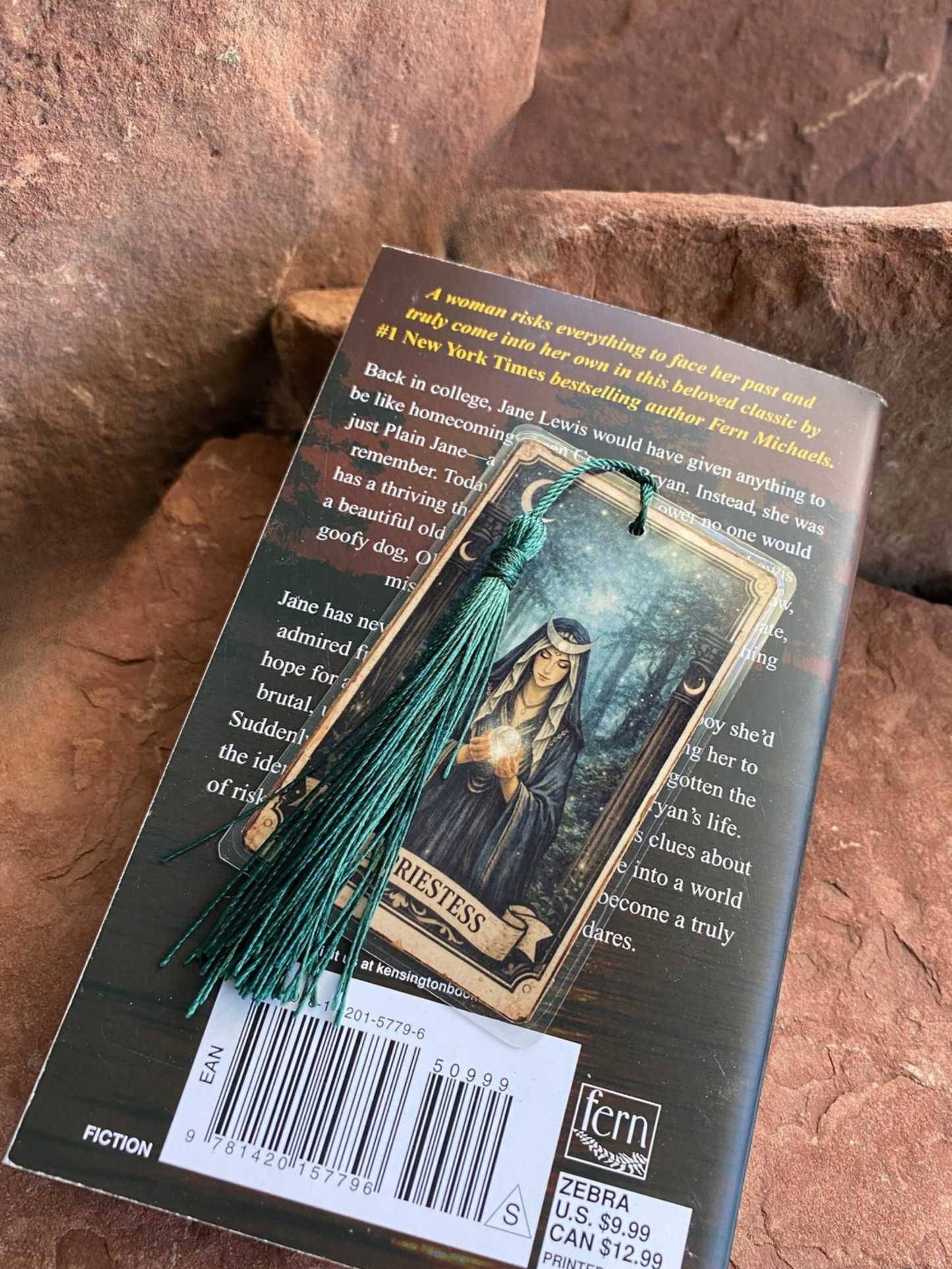 Book with a tassel bookmark on a stone surface. Small Bookmark shown on standard sized paperback for scale reference only