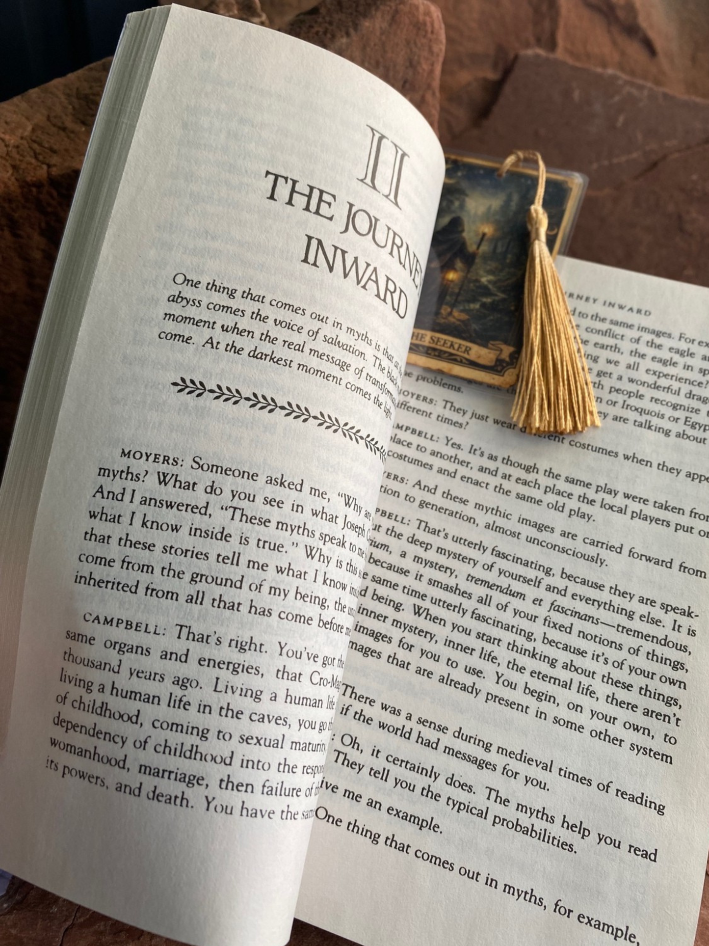 Open book with tassel on a wooden surface,. Small bookmark shown on oversized paperback for scale reference only