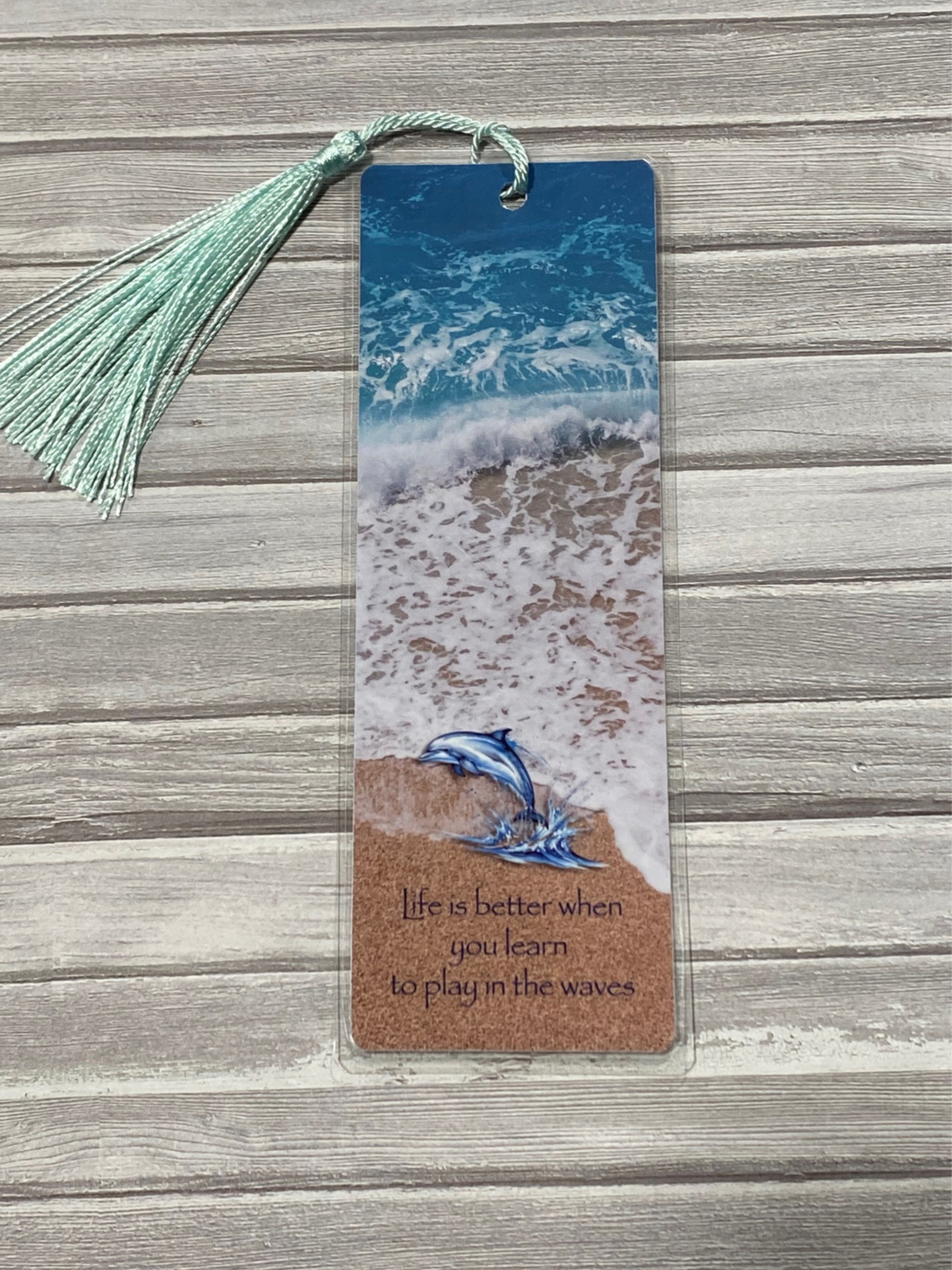 Bookmark with ocean design and dolphin illustration on a wooden surface