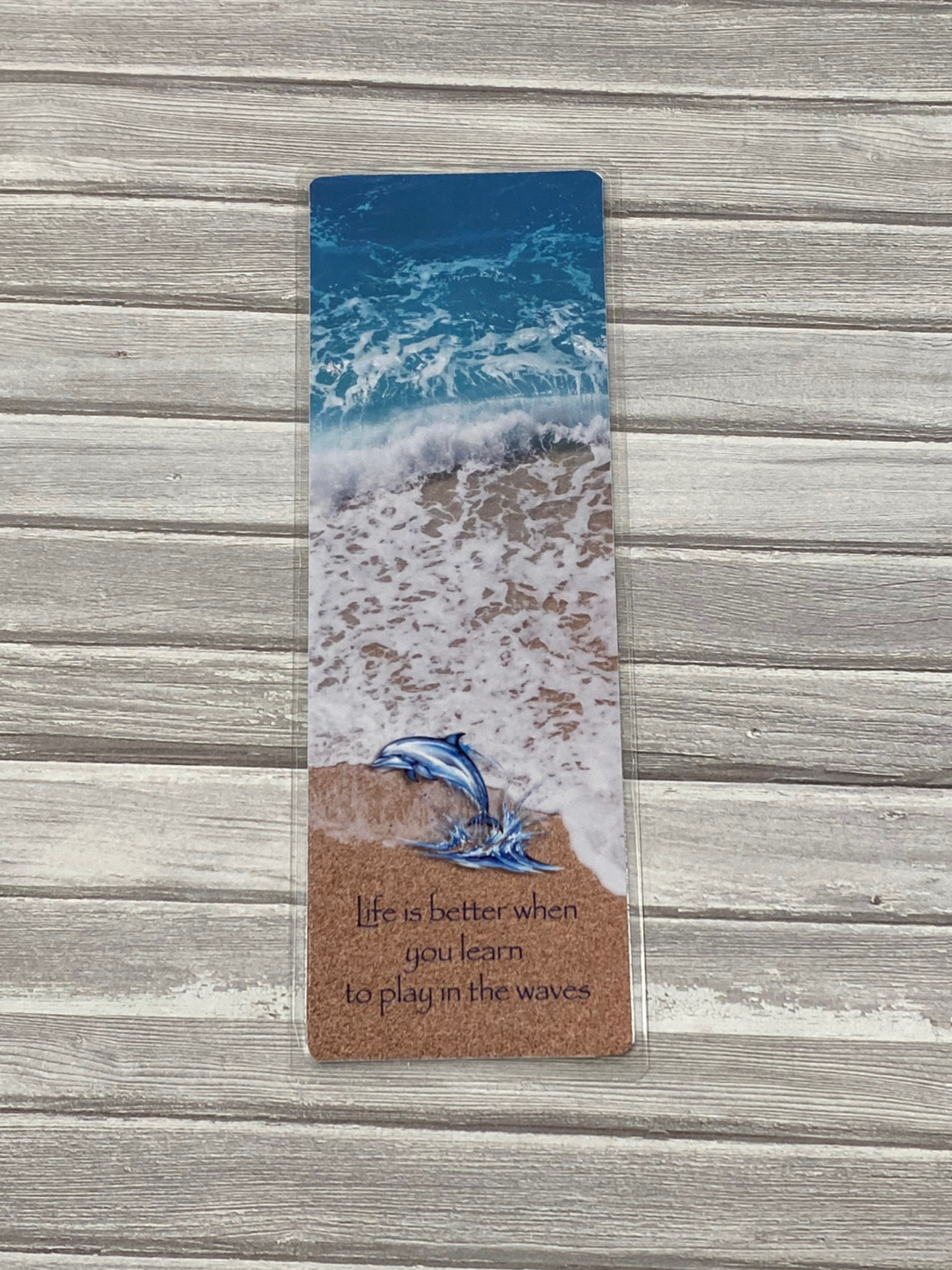 Bookmark with a dolphin and ocean design on a wooden surface