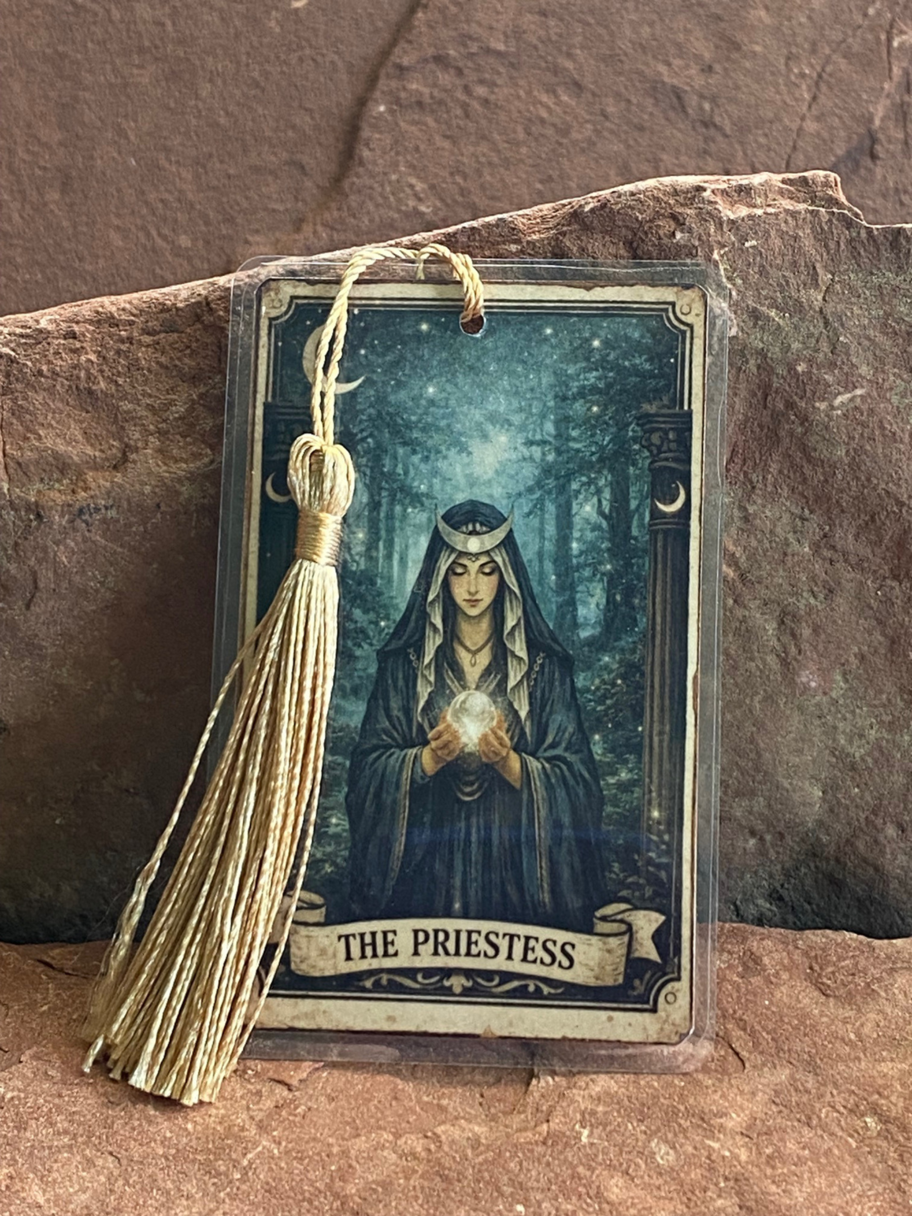 Card featuring 'The Priestess' with a tassel on a stone surface