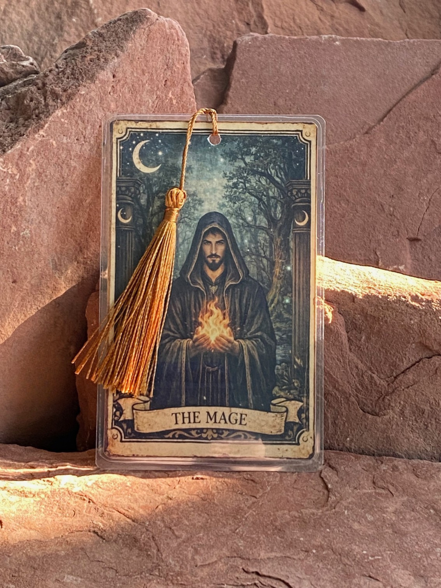 Card featuring a figure labeled 'The Mage' with a tassel, placed on stone surface