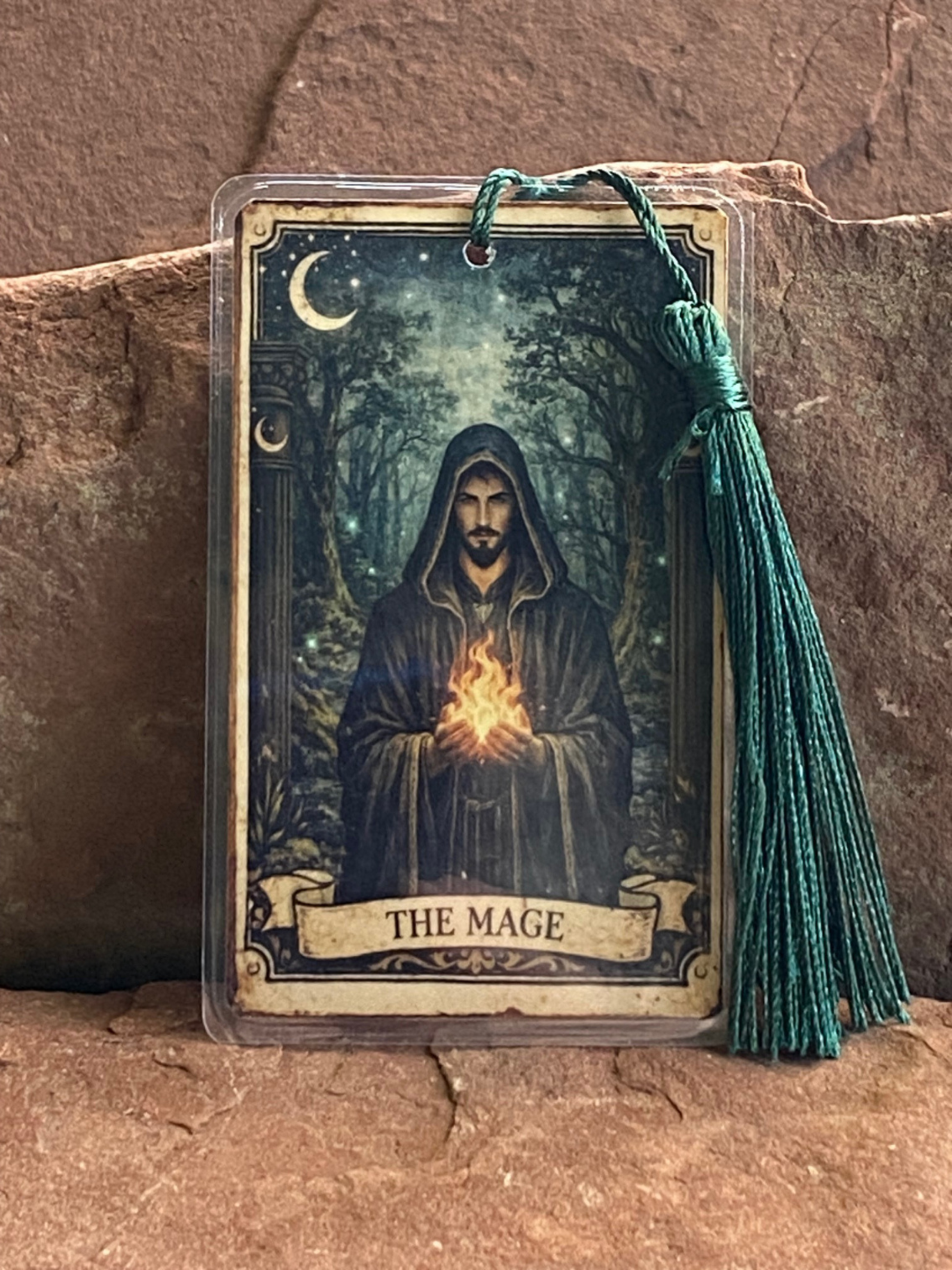 Card featuring a hooded figure with a glowing orb, labeled 'The Mage', on a stone surface.