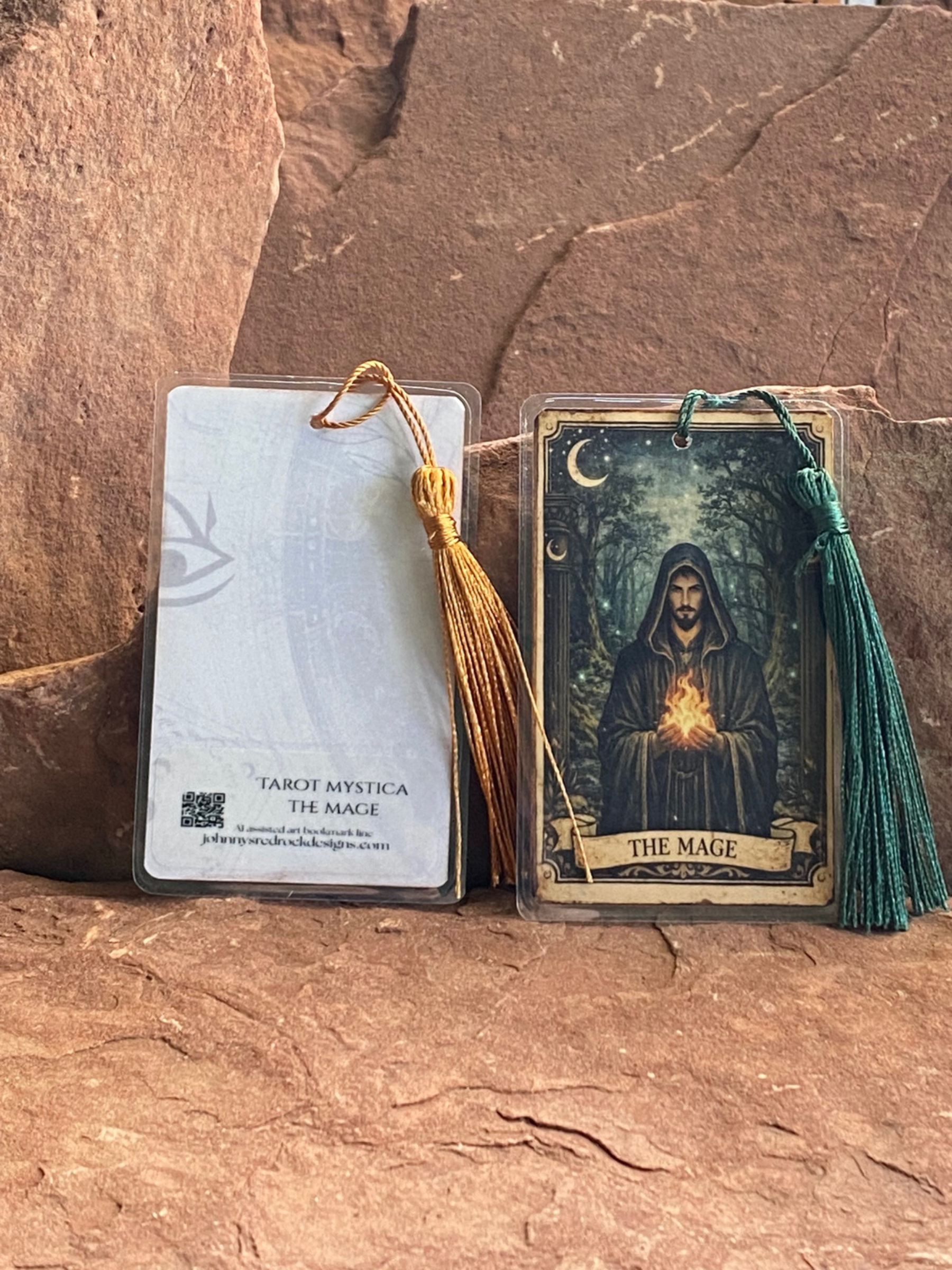 Two tarot cards with tassels on a stone surface, one featuring 'The Mage" and back of bookmark