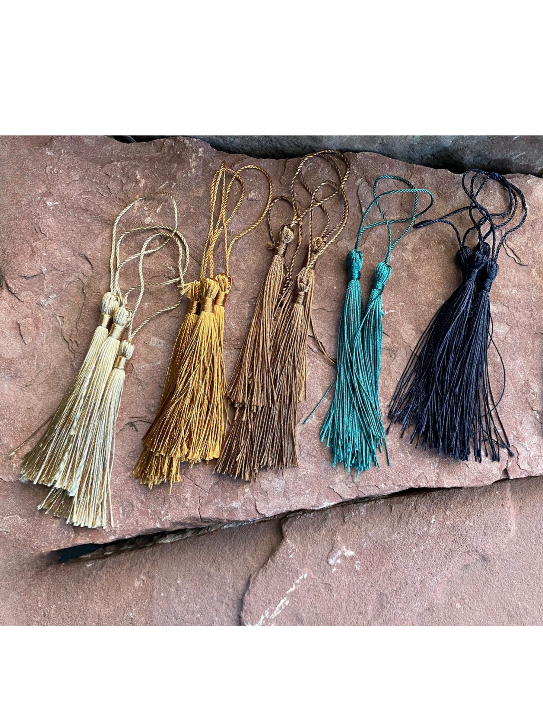 Set of five tassels in different colors on a stone surface