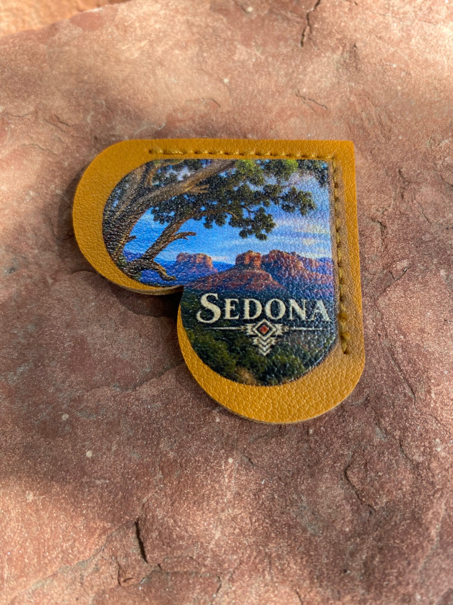 A heart-shaped leather patch with a mustard yellow border and a printed scenic landscape of Sedona, Arizona, featuring an oak tree, mountains, and the text 'SEDONA' on a rock surface.